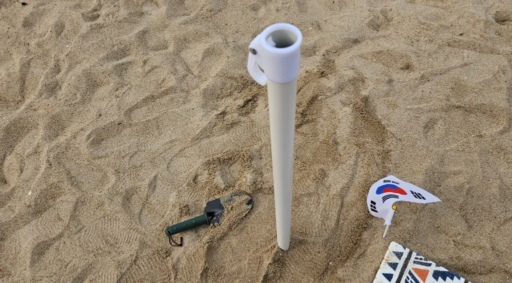 파라솔 봉 주변을 발로 단단하게 밟아 고정한 모습