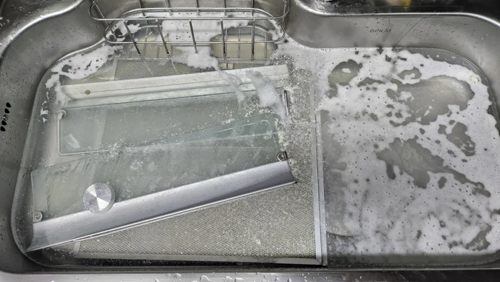 싱크볼에 뜨거운 물을 채우고 주방 후드 필터를 담근 후, 과탄산소다를 뿌려둔 모습