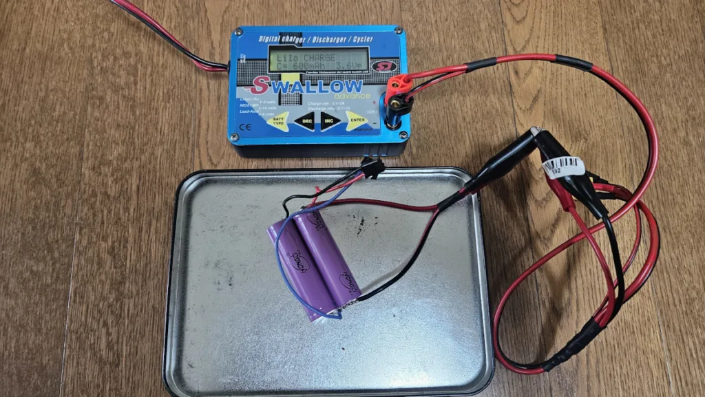 전압이 낮은 셀에 Li-ion 충전기를 연결한 모습. 충전 전류는 600mA로 설정했다. 화재나 폭발 우려를 고려해 금속 트레이 위해 배터리를 두었다
