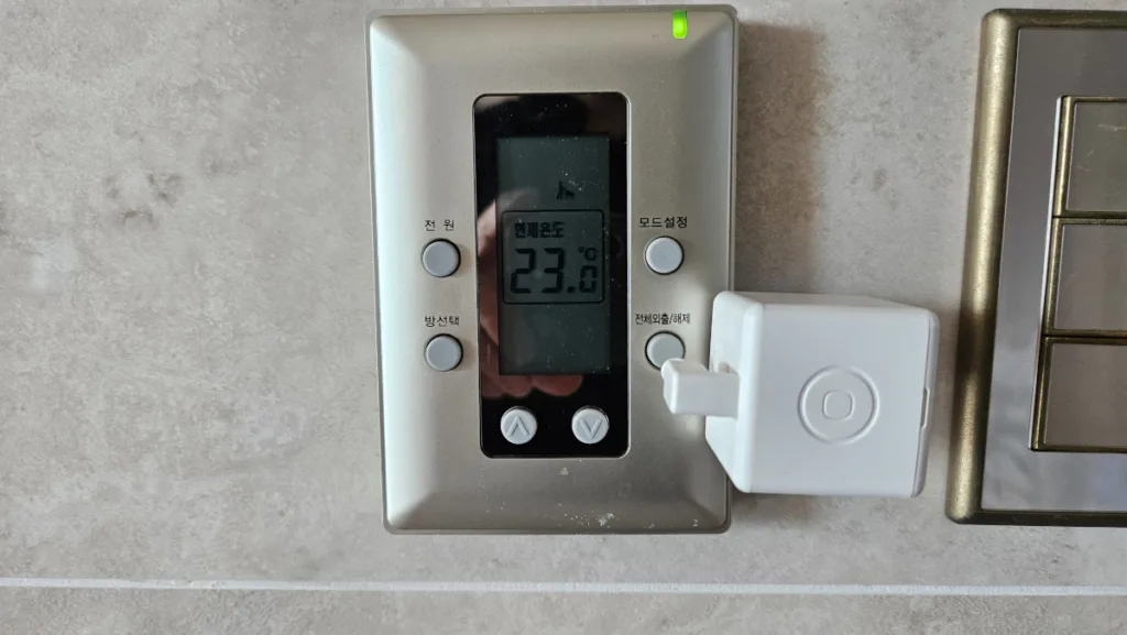 간헐식 난방을 위해 거실 난방 온도조절기 옆에 부착된 지그비 방식 핑거봇 모습